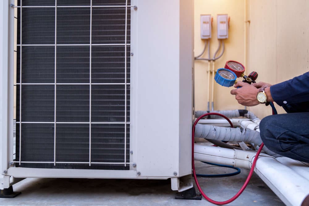Technician servicing a ductless mini-split air conditioning unit with pressure gauges in Tempe, Arizona, highlighting HVAC repair services.